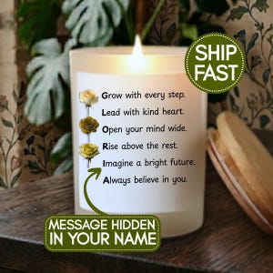 May include: A lit white candle with text that reads "Grow with every step. Lead with kind heart. Open your mind wide. Rise above the rest. Imagine a bright future. Always believe in you." The candle has a "Message Hidden in Your Name" label.