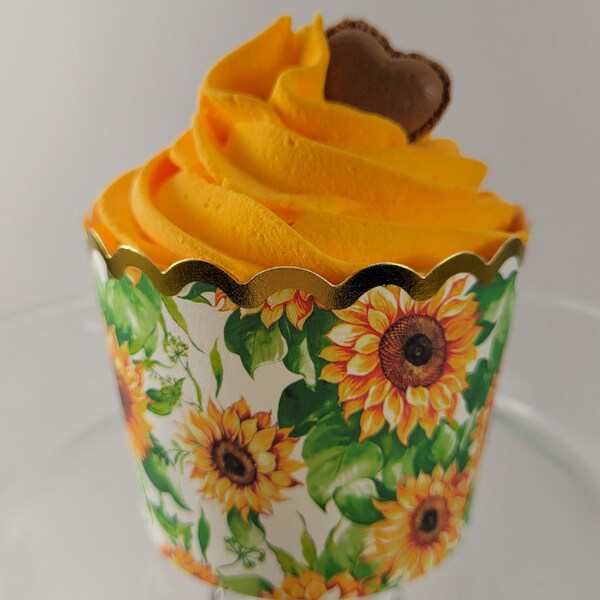 Sunflower Yellow frosted display cupcake in sunflower print cup with gold scallop trim and piece of heart shaped chocolate on top.