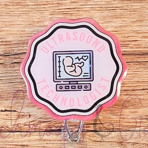 Może przedstawiać: Różowo-biały brelok do identyfikatora z czarno-białym wzorem, na którym widnieje napis "Ultrasound Technologist" oraz stylizowane zdjęcie dziecka w urządzeniu USG.