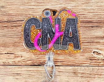 May include: Gold glitter badge reel with a black and pink stethoscope and the word "CNA" in black letters.