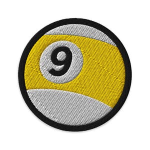 May include: Embroidered patch depicting a nine-ball design in yellow and white, with a black number 9. The patch has a black border. Suitable for application on clothing or accessories.