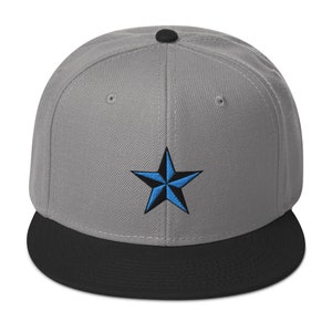 Puede incluir: Una gorra de béisbol gris y negra con un diseño de estrella azul y negra.