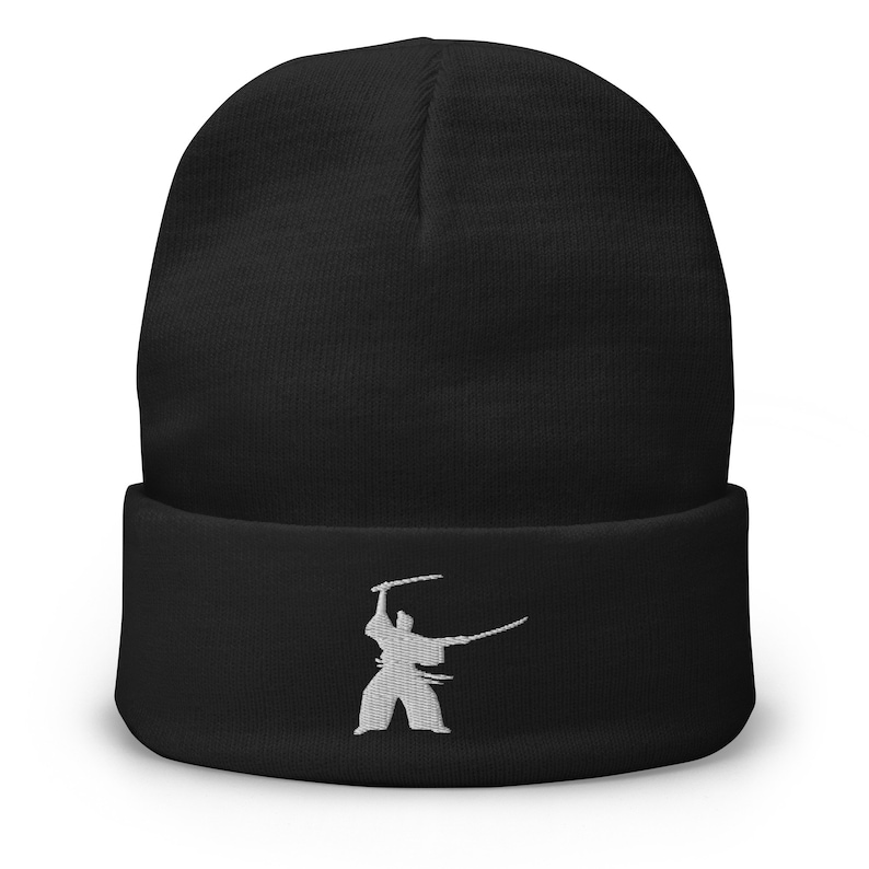 May include: Black beanie with a white embroidered silhouette of a person holding two swords.