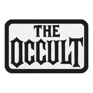 Puede incluir: Parche bordado con las palabras "THE OCCULT" en letras góticas negras sobre fondo blanco. El parche tiene un borde negro y es de forma rectangular.