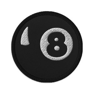 May include: Black and white embroidered patch of a billiard ball with the number 8 on it.