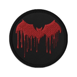 Puede incluir: Un parche bordado negro y rojo con una silueta de murciélago goteando. El murciélago es rojo y el fondo es negro.