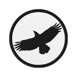 Puede incluir: Un parche bordado en blanco y negro con una silueta de un pájaro en vuelo dentro de un círculo negro.