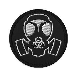 Pode incluir: Um remendo bordado preto com uma máscara de gás branca e um símbolo de risco biológico.