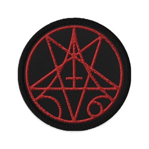 May include: A black and red embroidered patch featuring a pentagram design. The pentagram is outlined in red and has a red inverted cross in the centre.