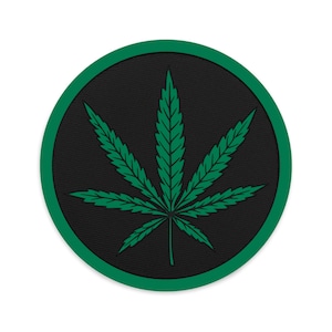 May include: A green marijuana leaf embroidered on a black circle patch with a green border.