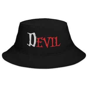 May include: Black bucket hat with the word "DEVIL" embroidered in white and red. The hat has a wide brim and a classic bucket hat shape. The text is in a gothic font.