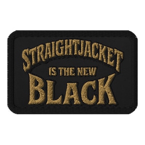 May include: Black rectangular patch with the embroidered phrase "STRAIGHTJACKET IS THE NEW BLACK" in gold lettering. The patch has a black border and a textured appearance.