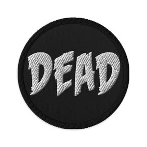 Può includere: Una toppa ricamata in bianco e nero con la parola "DEAD" in un font stilizzato.