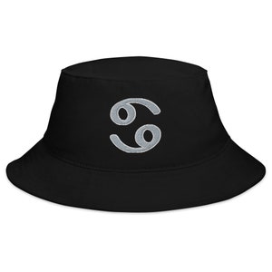 Puede incluir: Sombrero de pescador negro con un símbolo del zodíaco Cáncer bordado en plata.