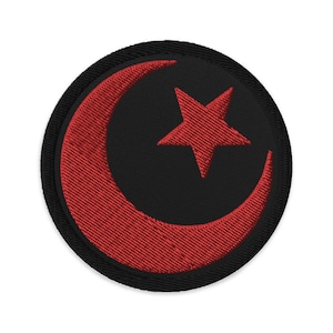 Op de afbeelding: Een geborduurde patch met een rode halve maan en een ster op een zwarte achtergrond.