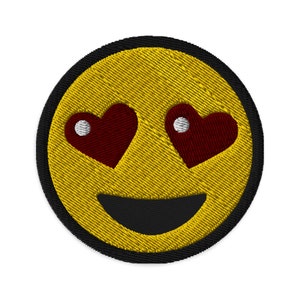 May include: Yellow smiley face with a black outline and a wide smile. The eyes are replaced with red hearts with white centers.
