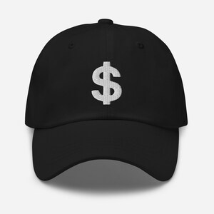 Puede incluir: Una gorra de béisbol negra con un signo de dólar blanco bordado en la parte delantera.