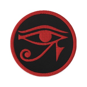 Könnte beinhalten: Roter gestickter Horus-Augen-Symbol auf einem schwarzen runden Patch.