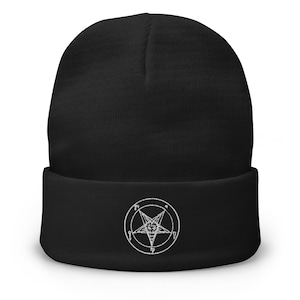 Può includere: Berretto nero con un simbolo pentagramma bianco ricamato. Il berretto è realizzato in morbido materiale a maglia e ha un risvolto. Il pentagramma è racchiuso in un cerchio con altri simboli.