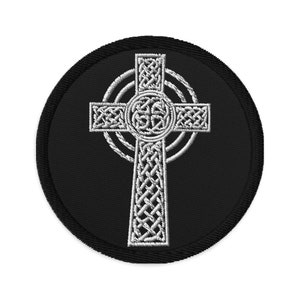 May include: A black patch featuring a white Celtic cross design. The cross is intricately detailed with interwoven patterns, set against a circular background. The patch has a black border.