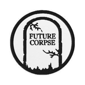 Pode incluir: Etiqueta bordada em preto e branco com um design de lápide. A lápide tem as palavras "FUTURE CORPSE" escritas nela.