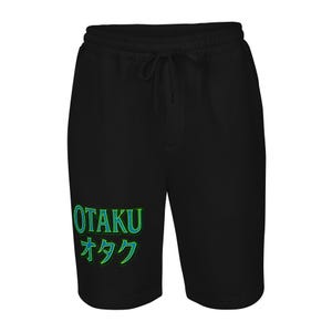 May include: Black shorts with a drawstring waist. The shorts feature the word "OTAKU" in green and blue, along with Japanese characters. The shorts are made of a soft material.