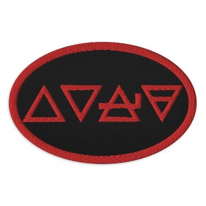 May include: A red embroidered patch with a black background and four red triangles arranged in a circle. The triangles are stylized to resemble the elements of earth, air, fire, and water.