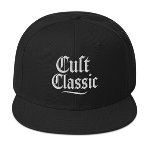Könnte beinhalten: Schwarze Baseballkappe mit flachem Schirm. Auf der Kappe ist der Text "Cult Classic" in weißer, gotischer Schrift gestickt. Ein klassisches Unisex-Accessoire.