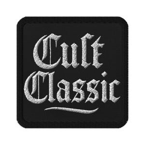 Puede incluir: Parche bordado cuadrado negro con la inscripción blanca "Cult Classic" en letras góticas. El parche tiene un borde negro y un aspecto texturizado.