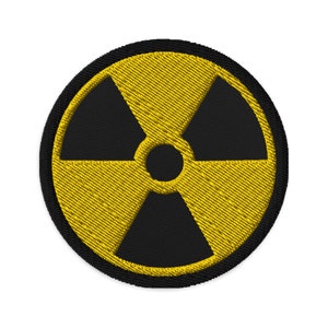 Peut inclure: Un écusson brodé jaune et noir avec un symbole de radiation.