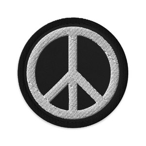 May include: A black and white peace sign patch. The peace sign is white and outlined in black. The patch is circular and has a black border.