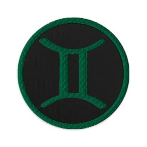 Puede incluir: Parche circular negro con un signo del zodíaco Géminis bordado en verde.