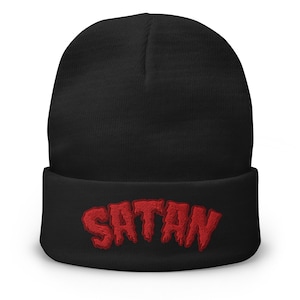 May include: Black beanie with the red embroidered word "SATAN" across the front. The beanie is a classic, cuffed style, suitable for cold weather. The bold text adds a statement to the simple design.