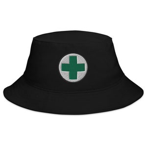 May include: Black bucket hat with a white circle and a green plus sign embroidered on the front.