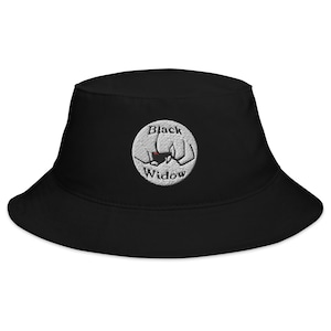 Op de afbeelding: Zwarte bucket hat met een geborduurd wit cirkellogo met de tekst "Black Widow" met een zwart spinnen silhouet in de cirkel.