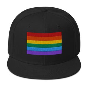 Peut inclure: Une casquette de baseball noire avec un drapeau arc-en-ciel brodé sur le devant.