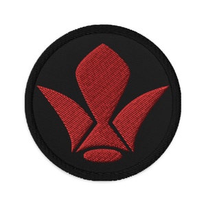 May include: A black and red embroidered patch with a stylized flower design. The flower has five petals and is red, while the background is black.