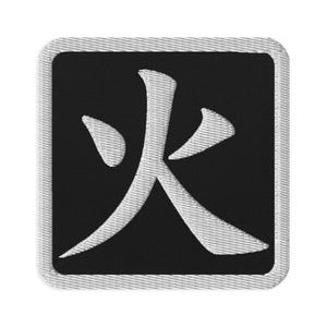 May include: A square embroidered patch featuring a black background with a white border and the white Japanese kanji character for fire centered in the middle. The patch has a visible stitched texture throughout the entire design.
