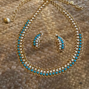 Puede incluir: Un collar y pendientes de oro con un dise&ntilde;o de cadena que presenta piedras turquesa y blancas alternadas.