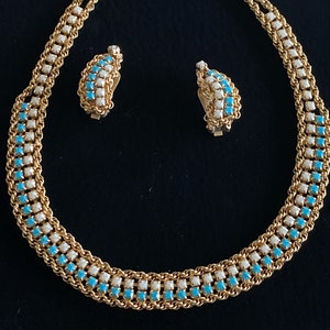 Puede incluir: Un collar y pendientes de oro con una doble fila de piedras turquesa y blancas alternadas.