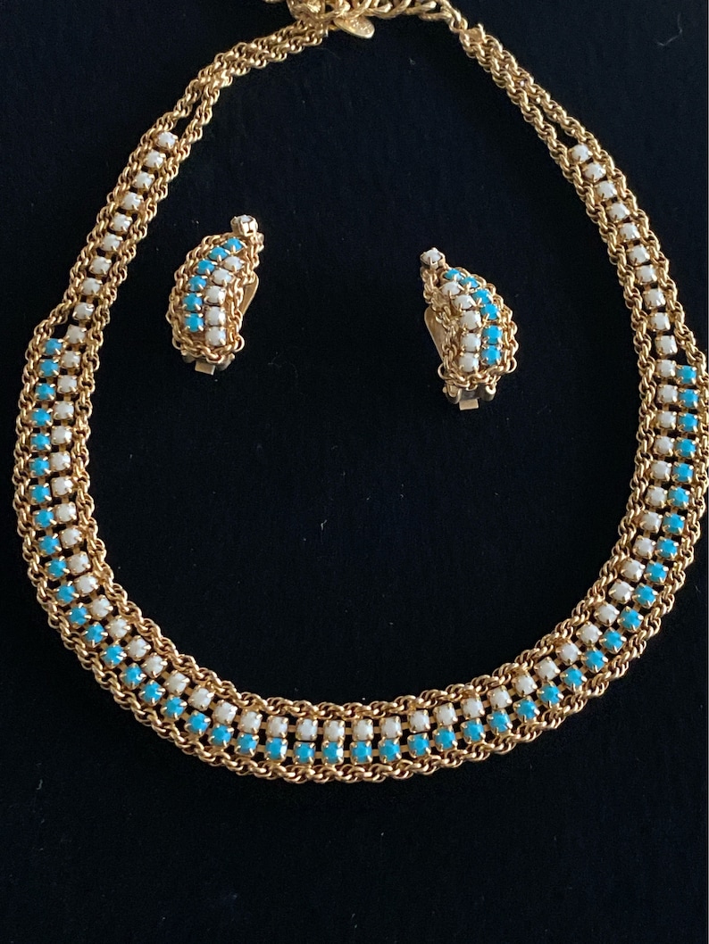 Puede incluir: Un collar y pendientes de oro con una doble fila de piedras turquesa y blancas alternadas.