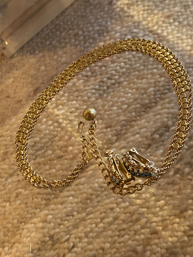 Puede incluir: Un collar de cadena de oro con un par de pendientes a juego. Los pendientes tienen peque&ntilde;as piedras azules y blancas.