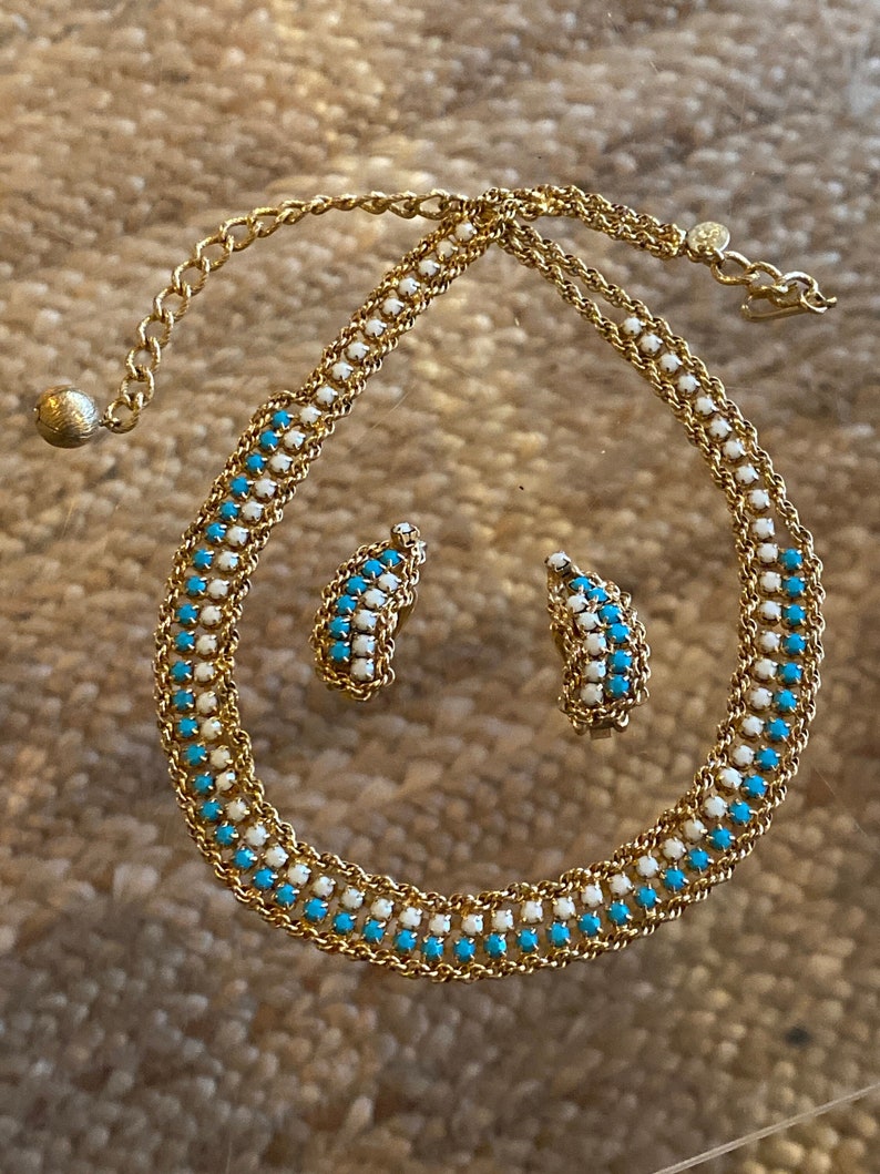 Puede incluir: Un collar y pendientes de oro con un dise&ntilde;o de cadena que presenta piedras turquesa y blancas alternadas.
