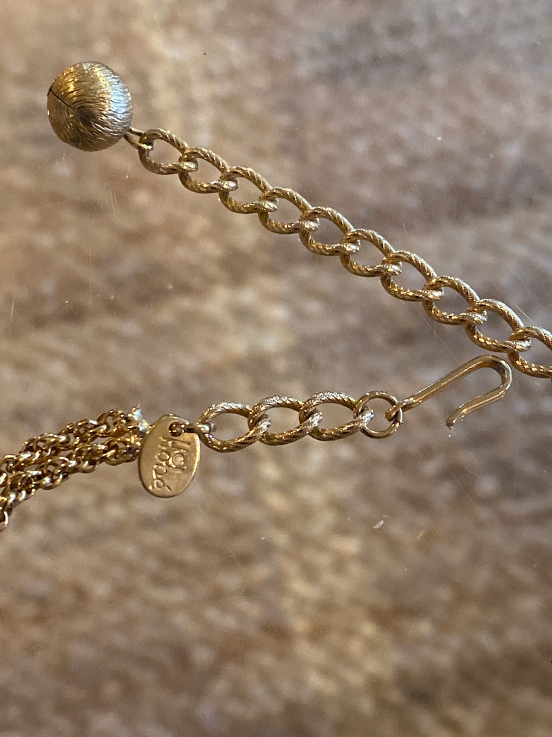 Puede incluir: Un collar de cadena de oro con un peque&ntilde;o dije redondo y un cierre de langosta. La cadena est&aacute; hecha de un dise&ntilde;o de cuerda trenzada. El dije tiene la palabra "Italia" grabada.