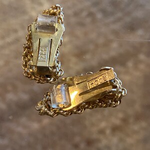 Puede incluir: Un par de pendientes de clip de tono dorado con un dise&ntilde;o de cadena. Los pendientes est&aacute;n marcados con "Hob&eacute;"