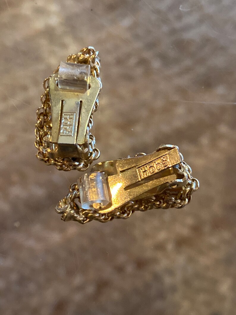 Puede incluir: Un par de pendientes de clip de tono dorado con un dise&ntilde;o de cadena. Los pendientes est&aacute;n marcados con "Hob&eacute;"