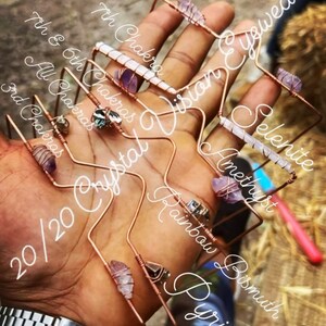 May include: A set of seven crystal wire-wrapped bracelets with various stones, including amethyst, selenite, rainbow pyrite, and bismuth. The bracelets are labeled with their corresponding chakras and the text "20/20 Crystal Vision Eyewear".