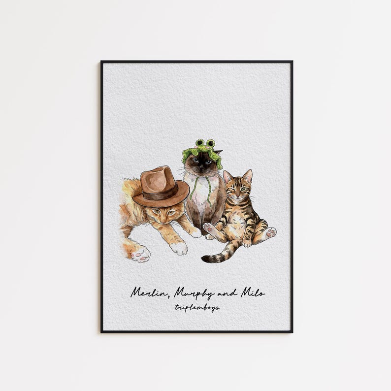 May include: Watercolor print of three cats, each with unique accessories. One cat wears a brown fedora, another a frog hat, and the third sits upright. The print is framed and features the text "Merlin, Murphy and Milo tripleboys."