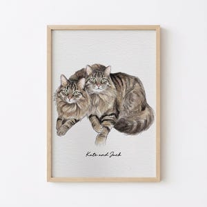 May include: Watercolor painting of two cats, one lying in front of the other. The cats have brown and black striped fur and green eyes. The text "Kate and Jack" is written in cursive at the bottom of the image.