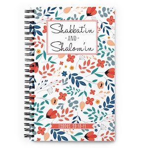 Puede incluir: Una libreta de espiral blanca con un patrón floral con flores rojas, naranjas, azules y verdes. El texto "Shabbat'in -AND- Shalom'in" está escrito en cursiva negra sobre un rectángulo blanco. El texto "EXODUS 20:10-11" está escrito en negro sobre un rectángulo rojo.